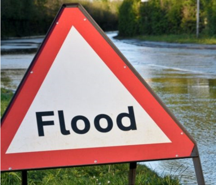 Flood sign and flooded street in the background